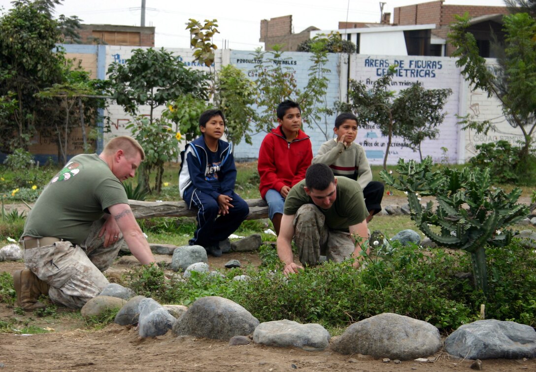 ANCON, Peru -- Marines clean up a rock garden at the elementary school. A combined US and Peruvian Marine Community Relations team visited the Almirante Miguel Grau Elementary School to participate in an all-day Community Relations project. Thirty Marines and two Navy enlisted from Special Marine Air Ground Task Force (SPMAGTF) 24, under the leadership of LCdr Michael Moreno, SPMAGTF 24 Chaplain, counting with the support of a platoon of Peruvian Marines, painted interior school classrooms, exterior walls and dug a 75-yard trench for a sprinkler system during the day visit.  (Official Marine Corps Photo)