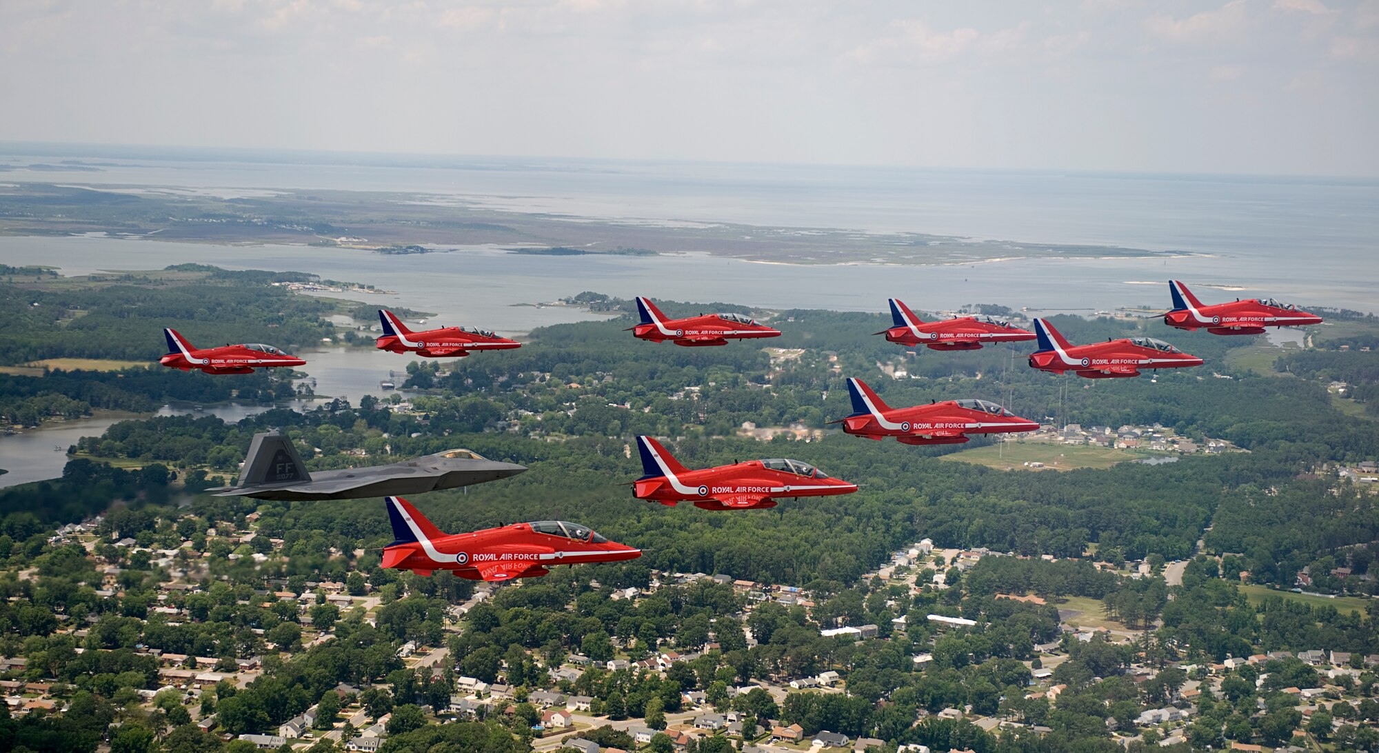 LANGLEY AIR FORCE BASE, Va. – Maj. Paul "Max" Moga, F-22A Raptor Demonstration Team pilot, flies in formation with British Royal Air Force Aerobatic Team, The Red Arrows, during an afternoon practice flight here June 18. Both demonstration teams will perform at AirPower over Hampton Roads, Langley’s air show, which is scheduled for June 20 to 22. (U.S. Air Force photo/Staff Sgt. Samuel Rogers)