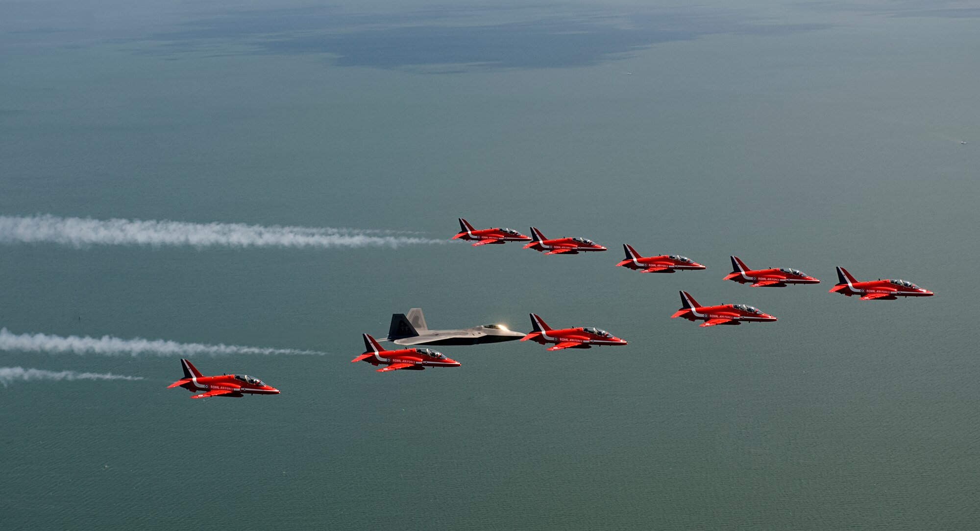 LANGLEY AIR FORCE BASE, Va. – Maj. Paul "Max" Moga, F-22A Raptor Demonstration Team pilot, flies in formation with British Royal Air Force Aerobatic Team, The Red Arrows, during an afternoon practice flight here June 18. Both demonstration teams will perform at AirPower over Hampton Roads, Langley’s air show, which is scheduled for June 20 to 22. (U.S. Air Force photo/Staff Sgt. Samuel Rogers)