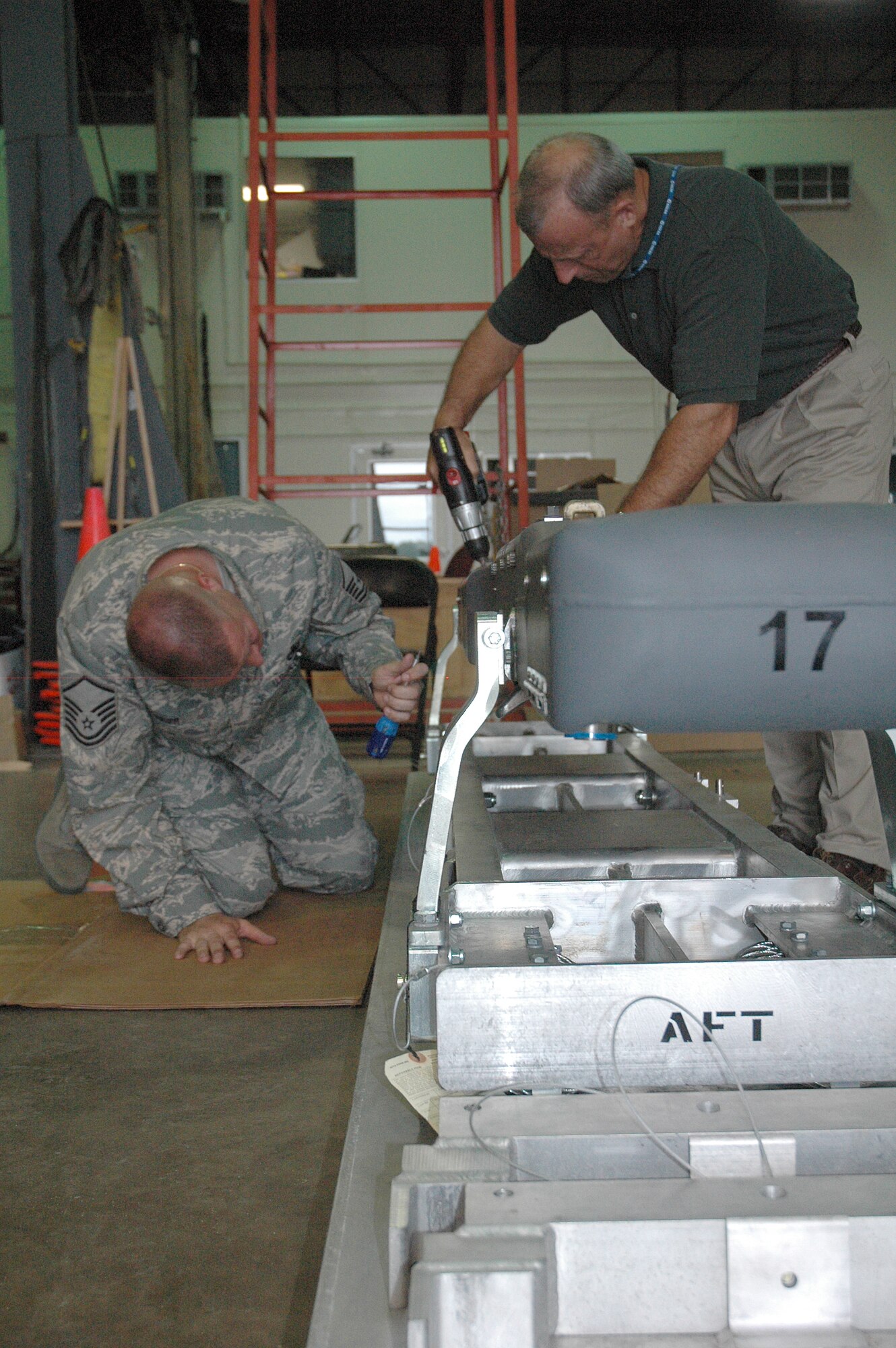 EGLIN AIR FORCE BASE, Fla. -- Master Sgt. Brian Mosier and Doug Davidson, 681st Armament Systems Squadron, tighten peices inside the pneumatic carriage system that holds and discharges the SDB to its carrier aircraft. (U.S. Air Force photo/Staff Sgt. Stacia Zachary)