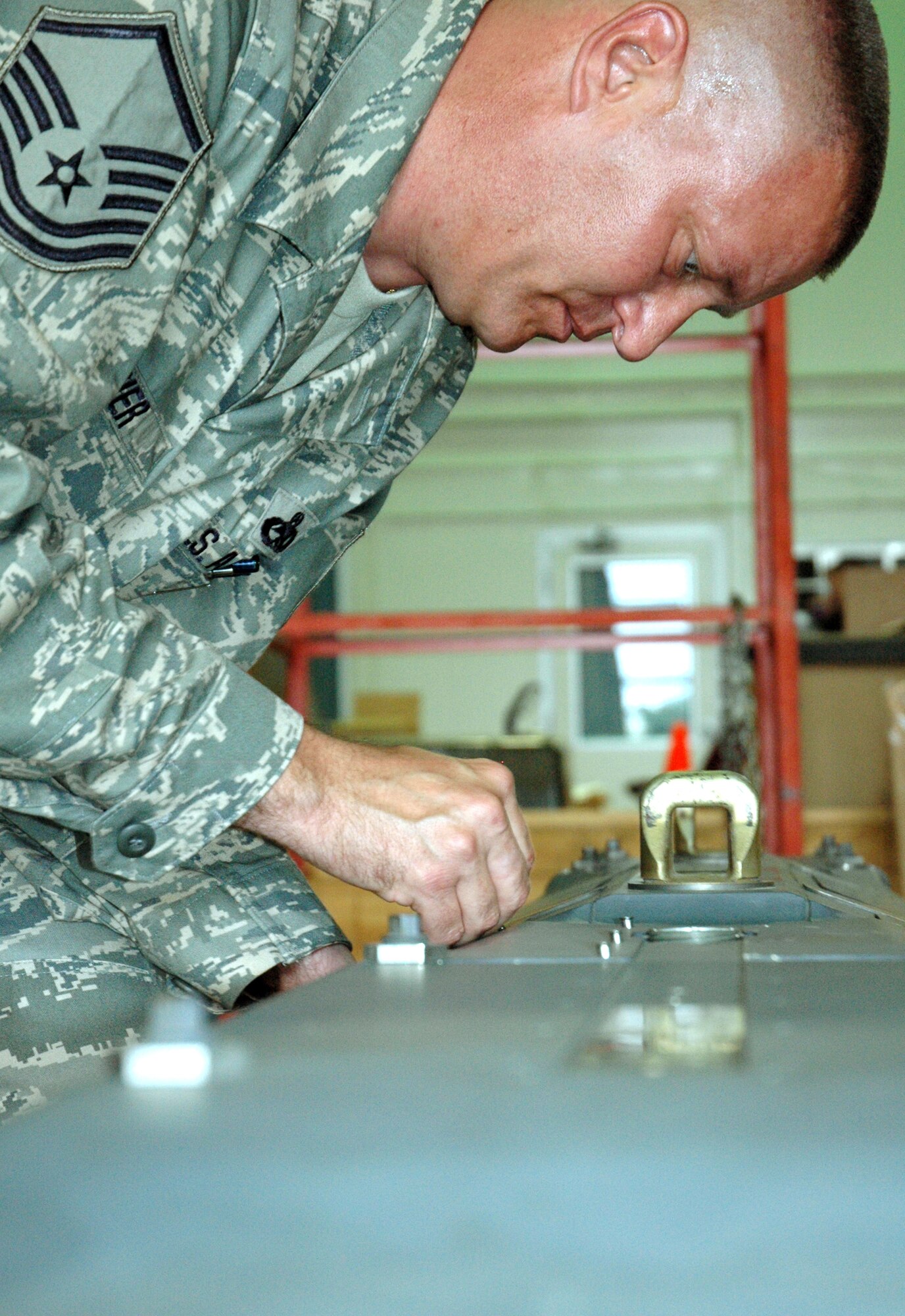 EGLIN AIR FORCE BASE, Fla. -- Master Sgt. Brian Mosier, 681st Armament Systems Squadron Small Diameter Bomb Logistics Team, tightens the screws to hold the cover of the pneumatic carriage system that holds and discharges the SDB to ists carrier aircraft. Sergeant Mosier is in the final stages addressing an issue detected with the carriage system. (U.S. Air Force photo/Staff Sgt. Stacia Zachary)