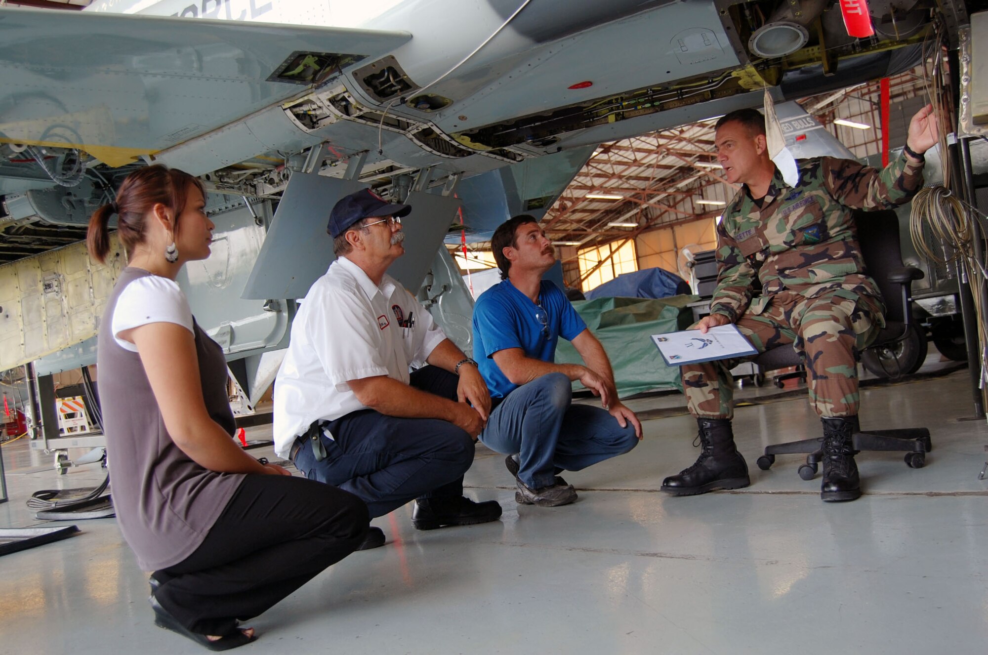 LAUGHLIN AIR FORCE BASE, Texas – Maribel Valdez, Summer Hire employee with the 47th Flying Training Wing public affairs office, and maintenance employees here listen to Col. John Doucette, 47th FTW commander, as he sits underneath a T-38 Talon and explains the importance of contractors working in the maintenance shops here.(U.S. Air Force photo by Airman 1st Class Sara Csurilla)