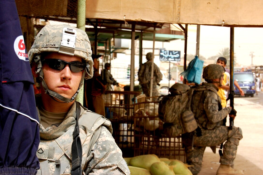 U.S. Army Pfc. Timothy Brown maintains security while patrolling a marketplace in Taji Qada, northwest of Baghdad, June 9, 2008, while military leaders visit a newly opened restaurant. Brown is an infantryman assigned to the 25th Infantry Division's 2nd Stryker Brigade Combat Team, 27th Infantry Regiment “Wolfhounds.” 