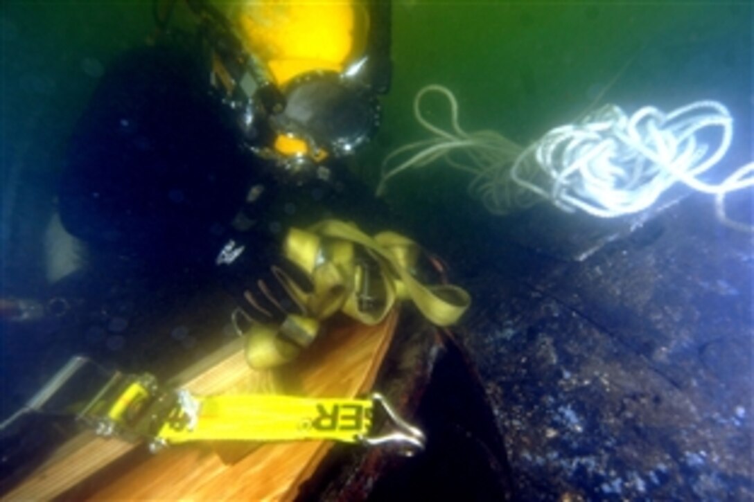 U.S. Navy Petty Officer 1st Class Mark Sawyer places a ratchet strap across a large patch that will be used to seal one of the escape hatches of the sunken former Soviet submarine Juliett 484 at the bottom of the Providence River, Providence, R.I., June 13, 2008. U.S. Navy and Army divers with federal, state, and local authorities are in a joint operation to raise the submarine.