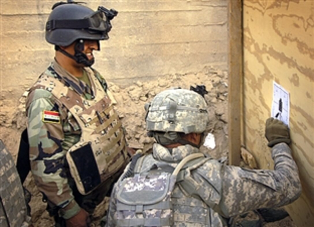 U.S.Army Sgt. Edgar Morales checks an Iraqi soldier's shot group results after firing, June 15, 2008. The weapons proficiency training was provided by U.S. soldiers at Joint Security Station Rashid in the Sadr City area of Baghdad, Iraq.  

