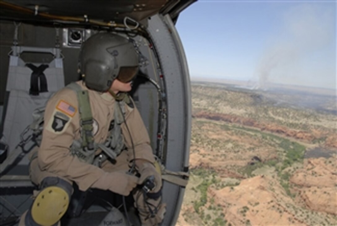 U.S. Army Sgt. Rick D. Peevy, a crew chief from Alpha Company, 2nd Battalion, 135th Aviation Regiment, Colorado Army National Guard, surveys the scene while wildfires burn the training range at Fort Carson, Colo., on June 12, 2008.  Peevy and his helicopter crew dropped approximately 22,000 gallons of water to help fight the fires burning in an estimated 30,000 acre area.  Personnel and Blackhawk helicopters from the Colorado Army National Guard have been assisting several other agencies in battling the blaze since June 9.  