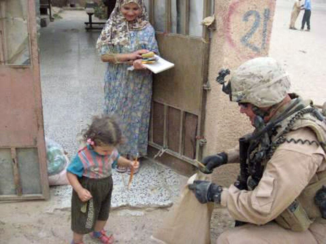 1st Lt. Brian Green, platoon commander of MAP 1, hands out school supplies to Iraqi children. More than 45 bags of school supplies and 20 bags of food were donated by teachers and students of the Oswego, Ill., Public School District #308.