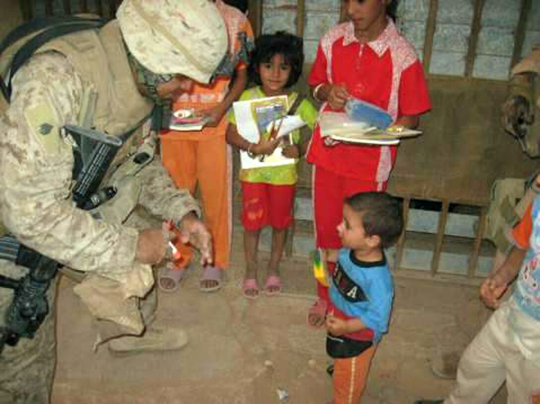 Staff Sgt. Marco Gomez, platoon sergeant of MAP 1, prepares to give an Iraqi boy school supplies during a mission May 10. The children and their parents were elated while receiving the supplies, which left a smile on the Marines faces.::r::::n::