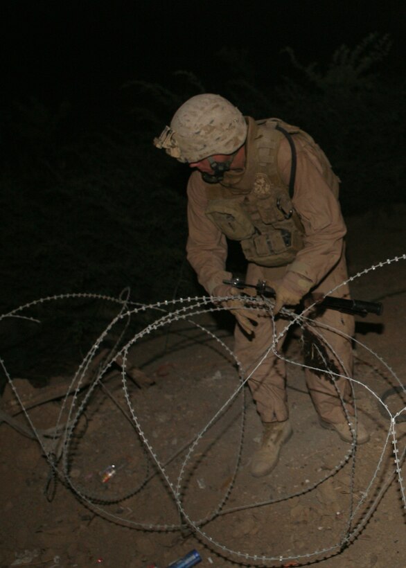Lance Cpl. Kristopher McKenzie, a 20-year-old radio operator from Glendora, Calif., with 2nd Combat Engineer Battalion, attached to 1st Battalion, 9th Marine Regiment, Regimental Combat Team 1, clears up concertina wire from the streets in Ramadi June 18. The removal of all the barriers much like the fall of the Berlin wall is not the removal of signs of war, but the symbolism of demilitarizing a city that hosted some of the most brutal house to house fighting Marines have seen since Hue City in Vietnam.