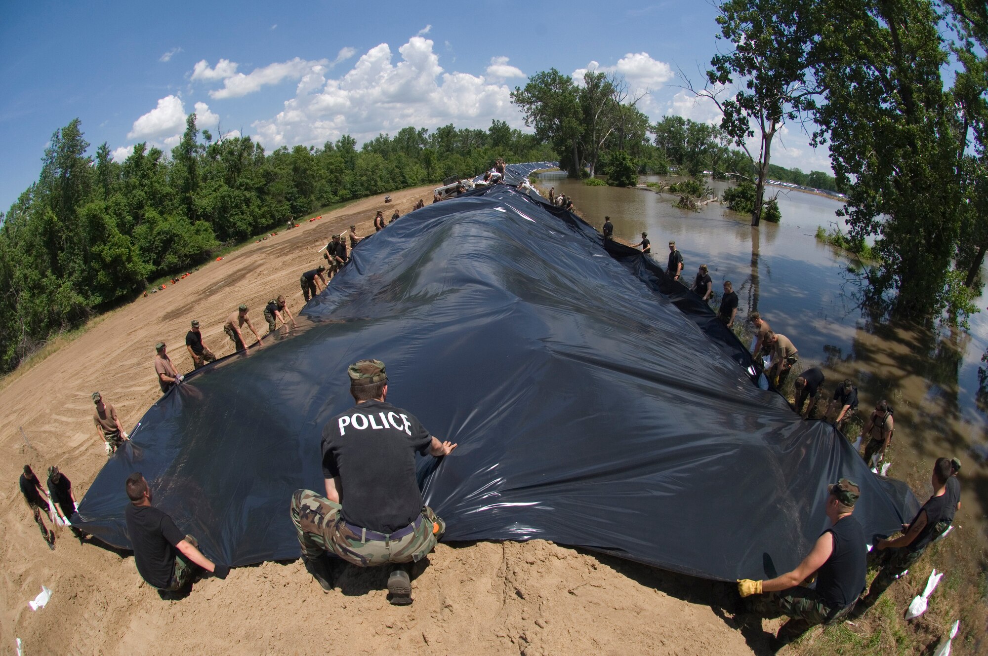 Airmen from the Illinois Air National Guard spread sheets of plastic over reinforced levees along the Mississippi River June 19 near Pleasant Hill, Ill. The plastic sheets prevent erosion that could cause the levee to fail and flood thousands of acres of farmland and homes. (U.S. Air Force photo/Master Sgt. Jack Braden) 