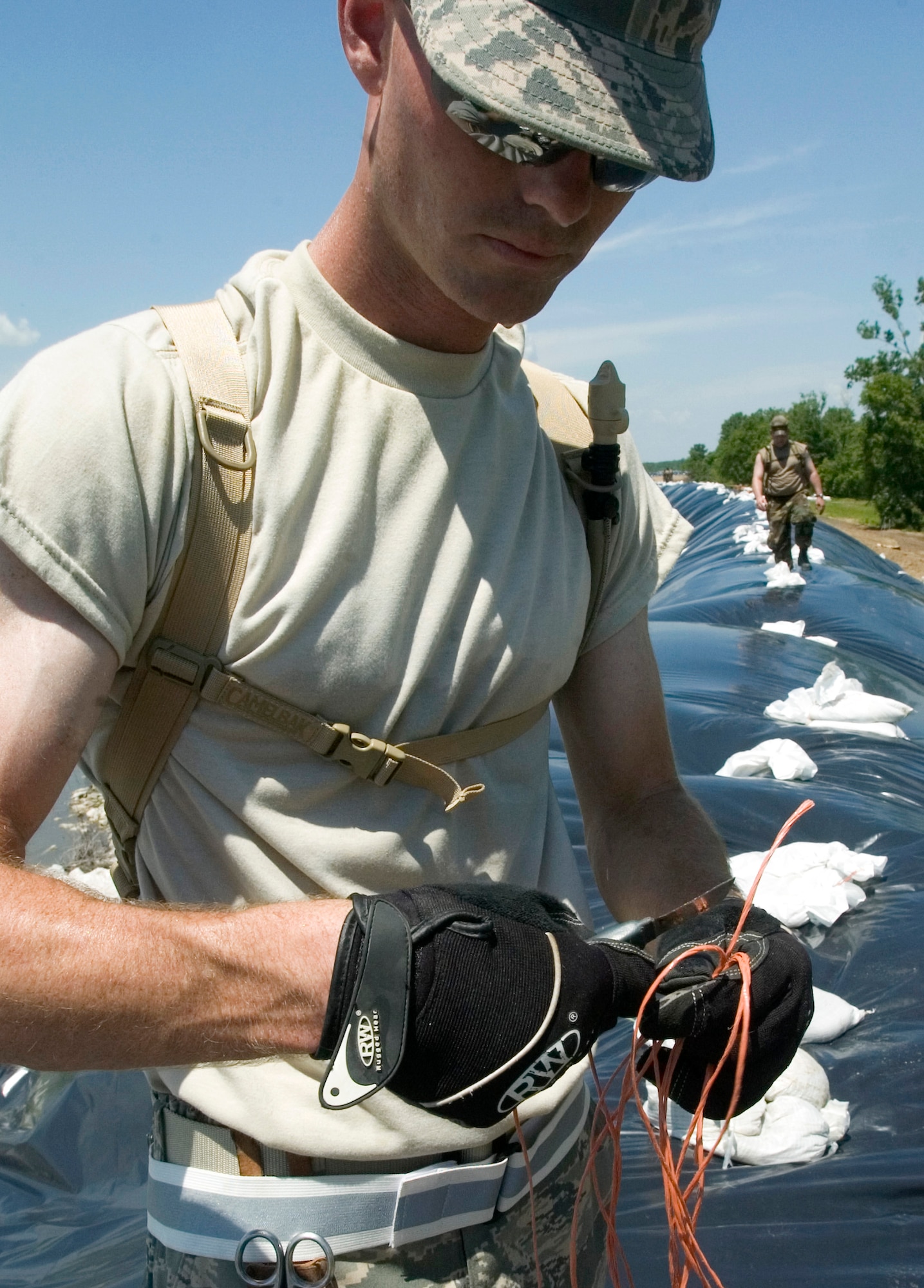 Staff Sgt. Eric Bell cuts rope to secure sand bags in place June 19 to help prevent erosion of the Sny levee near Pleasant Hill, Ill. The Sny levee protects communities along the Mississippi River for 52-miles. Airman Rath is an Air National Guardsman assigned to the 183th Fighter Wing located in Spring Field, Ill. (U.S. Air Force photo/Staff Sgt. Desiree N. Palacios) 