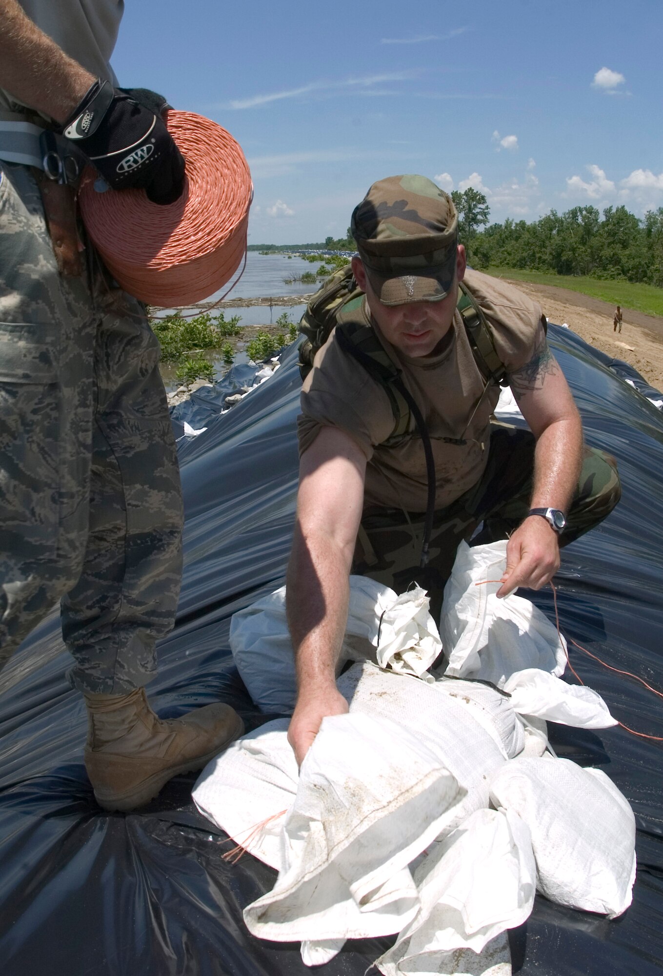 Senior Airman Aaron Rath secures two sand bags with rope June 19 to help prevent erosion along the Sny levee near Pleasant Hill, Ill. The Sny levee protects communities along the Mississippi River for 52-miles. Airman Rath is an Air National Guardsman assigned to the 183th Fighter Wing located in Spring Field, Ill. (U.S. Air Force photo/Staff Sgt. Desiree N. Palacios) 