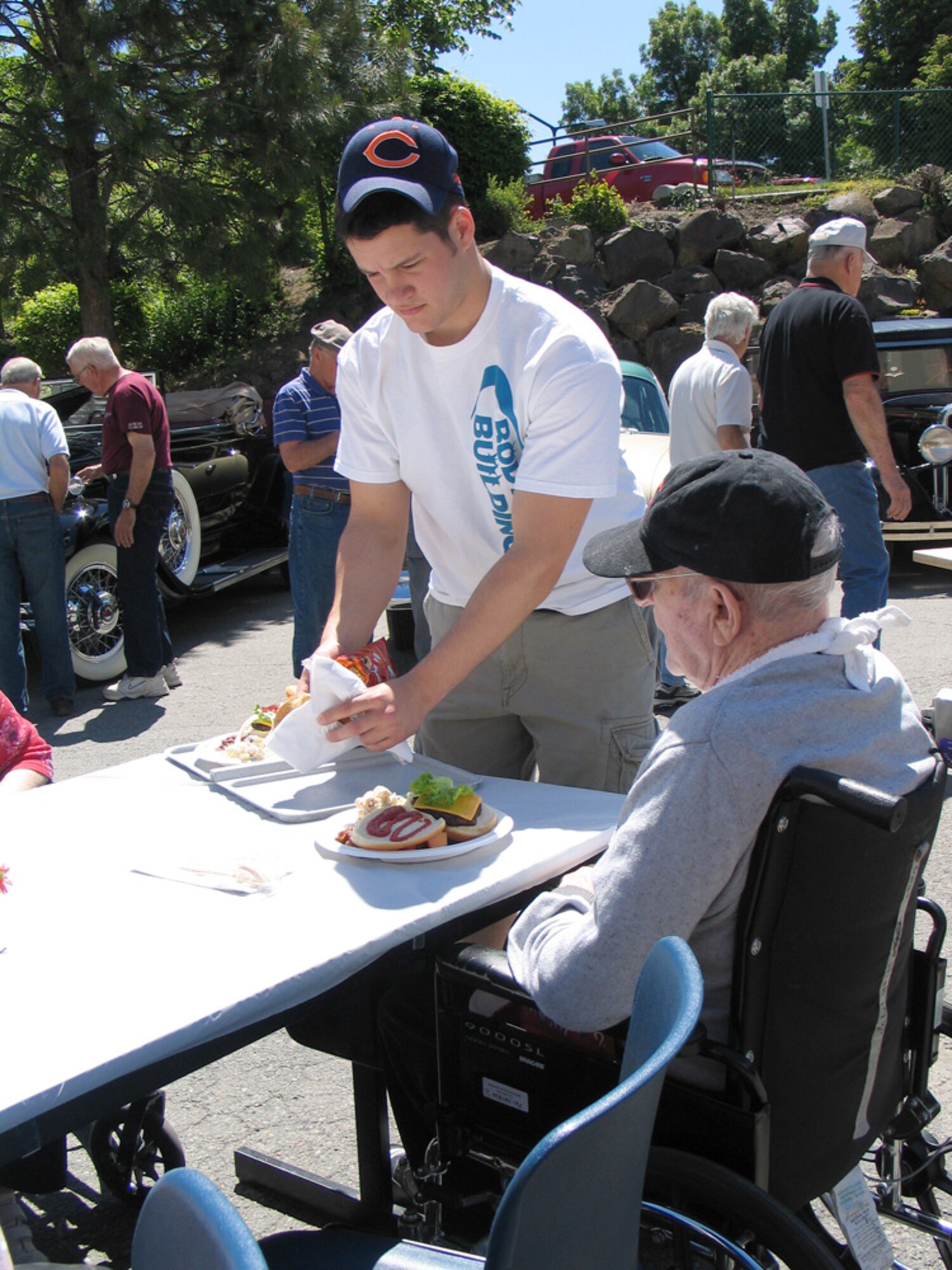FAIRCHILD AIR FORCE BASE, Wash. – Airman Matthew Wojciechowski, 92nd Medical Group, serves food to a resident of the Spokane Veterans Home June 14. More than 20 Fairchild volunteers helped set up and tear down equipment, and grill and serve food at the home’s annual Father’s Day barbeque. The volunteer opportunity was hosted by the Fairchild 5/6 Club. (U.S. Air Force photo / Staff Sgt. Connie L. Bias)