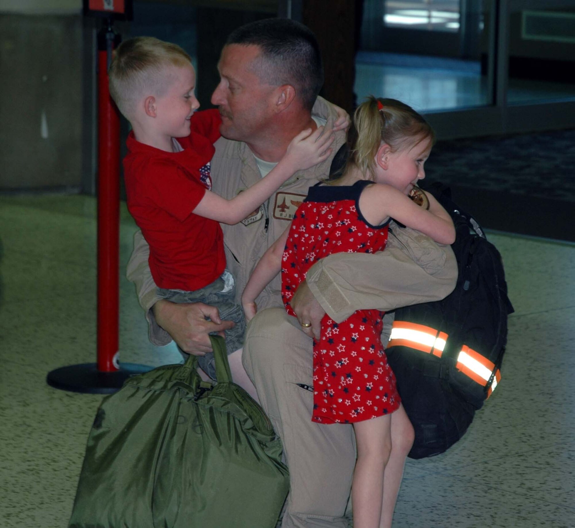 Lt. Col. Robert Buchanan, 944th Operations Support Flight commander, hugs his children, Kyle and Kori, June 19 after returning home from a deployment to Joint Base Balad, Iraq. Colonel Buchanan deployed with the 124th Fighter Squadron of the Des Moines Iowa Air National Guard flying F-16s over Iraq. (U.S. Air Force photo/Tech. Sgt. Susan Stout) 