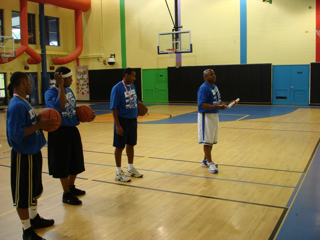 ANDREWS AIR FORCE BASE, Md. -- Pitman Kennedy, right, talks to his team at the  Youth Basketball Camp on at the Andrews Youth Center as assistant coaches Steve Wilcox, Carlos Rance and Vince Jones look on. Coach Kennedy was selcted as one of the Coaches of the Year for the Jr. National Basketball Association and Women's NBA in a nationwide competition.