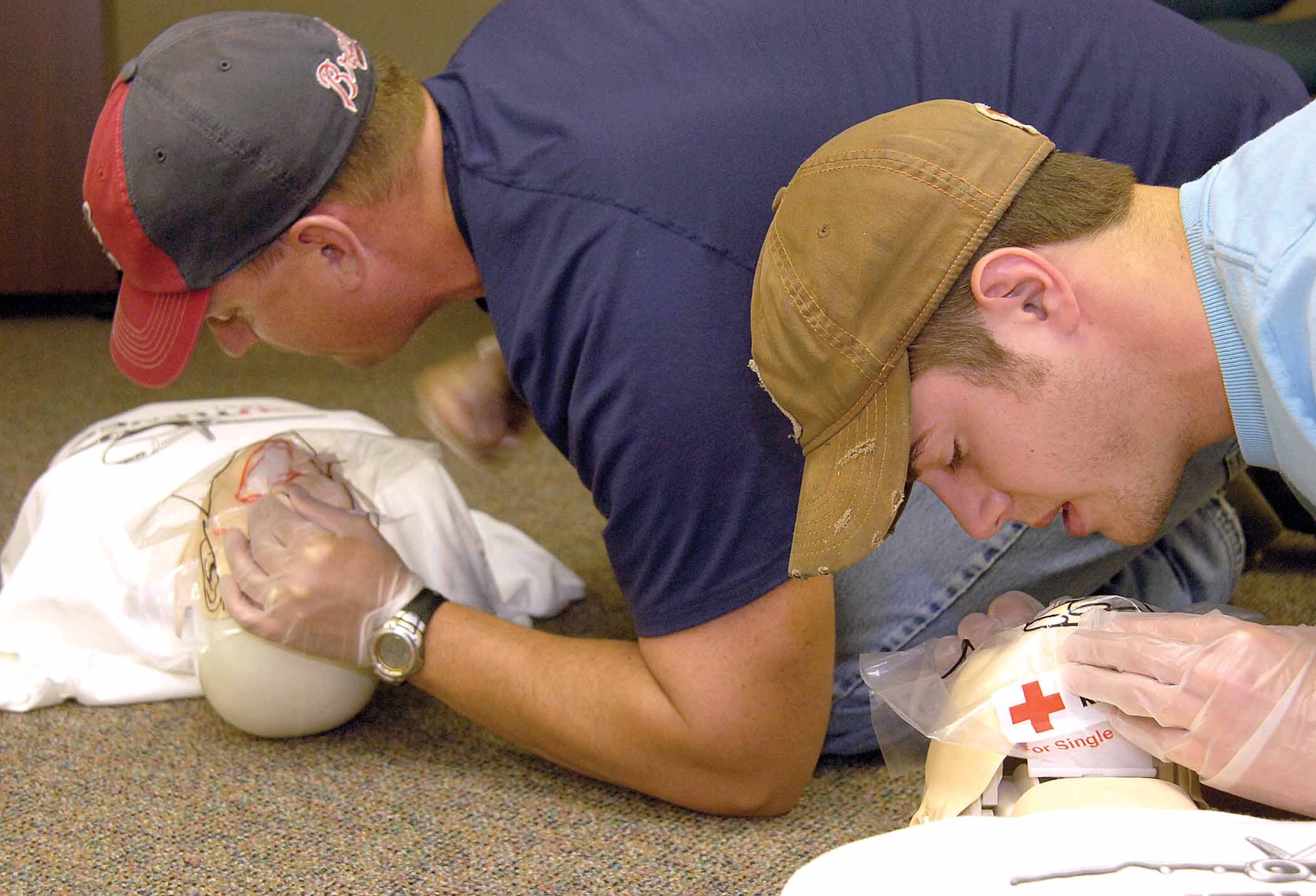 Tinker aircraft maintainers Jason McNully, back, and Mike Farris practice rescue breathing on CPR mannequins during a base June 10 First Responders class.  The men were part of a class by 76th Software Maintenance Group personnel teaching American Red Cross first aid, taking self aid and buddy care knowledge to the depot floor. (Air Force photos by Margo Wright)