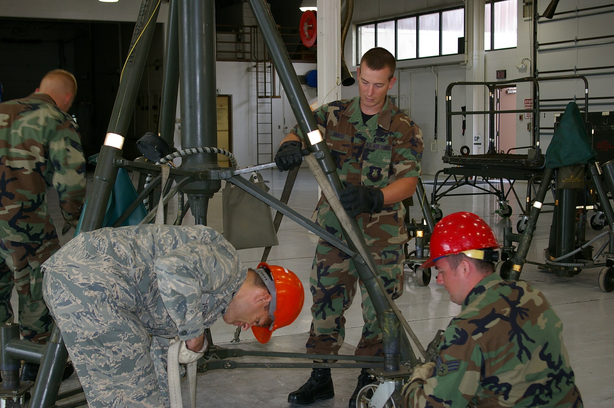 MCCONNELL AIR FORCE BASE, Kan. -- Airman 1st Class Allan Shurtz and Senior Airman Charles Hatton, 22nd Maintenance Squadron, Air Ground Equipment flight, assist Col. James C. Vechery, 22nd Air Refueling Wing commander, secure a 30-ton aircraft tripod jack for shipment in preparation for this week’s operational readiness exercise and next week’s operational readiness inspection, June 13. Aircraft jacks are used to raise an aircraft aloft. (photo by Staff Sgt. Thomas Sibert)