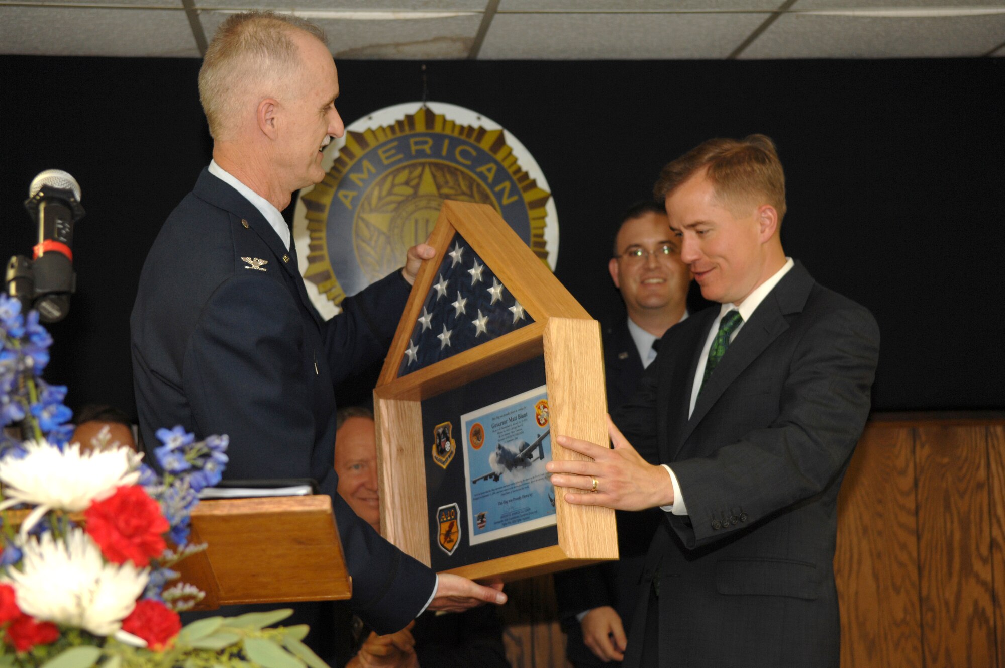 Col. Steve Arthur, left, presents Missouri Governor Matt Blunt with an American flag flown on a combat mission over Afghanistan and certificate following a bill-signing ceremony in Warrensburg, Mo., June 11, 2008.  Colonel Arthur is the commander of the 442nd Fighter Wing, an Air Force Reserve Command A-10 unit based at Whiteman Air Force Base, Mo.  The presentation also included two patches and a replica 30-millimeter bullet, which is fired from the gun mounted on the front of the A-10 Thunderbolt II.  Governor Blunt visited Warrensburg to sign Missouri House Bill 1678, which provided education relief to children of military members in Missouri.  In 2006 Governor Blunt visited deployed members of the 442nd Fighter Wing in Afghanistan and presented them with a Missouri state flag, which was flown over the flightline during that deployment.  The flag presented to the governor was flown in an A-10 on Sept. 11, 2006, five years after the attack on the World Trade Center buildings in  New York and on the Pentagon.  (U.S. Air Force photo/Senior Airman Jessica Snow) 