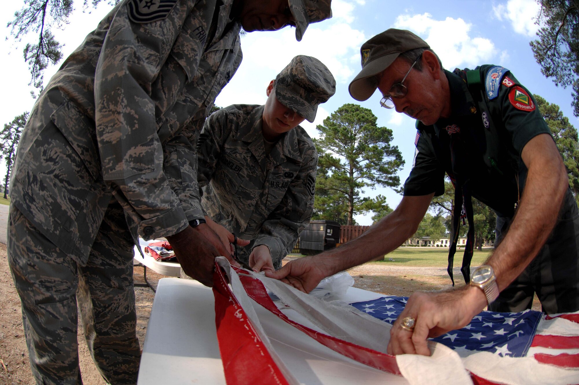 SEYMOUR JOHNSON AIR FORCE BASE, N.C. Command Chief Master Sgt. Leroy Frink, Staff Sgt. Jessica klingler and Troop 8 Leader Dewey Offield cut an American flag for a flag retirement ceremony, June 14 2008. (U.S. Air Force photo by Airman 1st Class Gino Reyes)