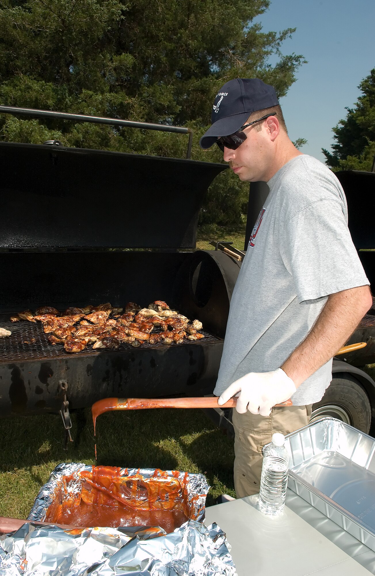 Master Sgt. Michael Bacu, 436th Logistics Readiness Squadorn, prepares to add more barbecue sauce to the chicken on the grill at the Wing Picnic.  Members of the Top 3 Association cooked the chicken, hamburgers and hot dogs for Team Dover members at the Eagles Nest Picnic Area.  (U.S. Air Force Photo by Jason Minto)