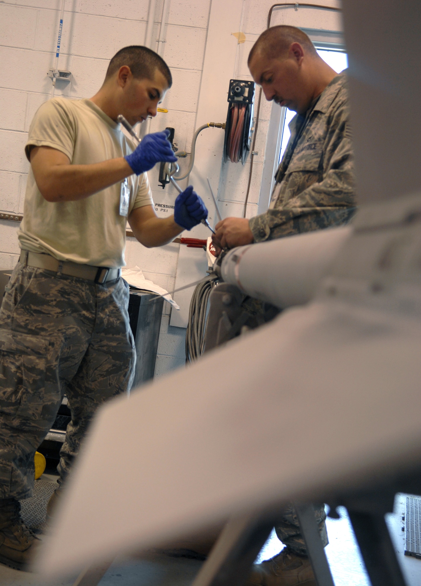SEYMOUR JOHNSON AIR FORCE BASE, N.C. - Airman Ben Hutchinges and Staff Sgt. Douglas Retcher, both from the 4th Equipment Maintenance Squadron, attach fins to an AIM-9 missile here May 21. The fins are attached to the missle to give it more stability in flight. (U.S. Air Force photo by Airman 1st Class Gino Reyes)