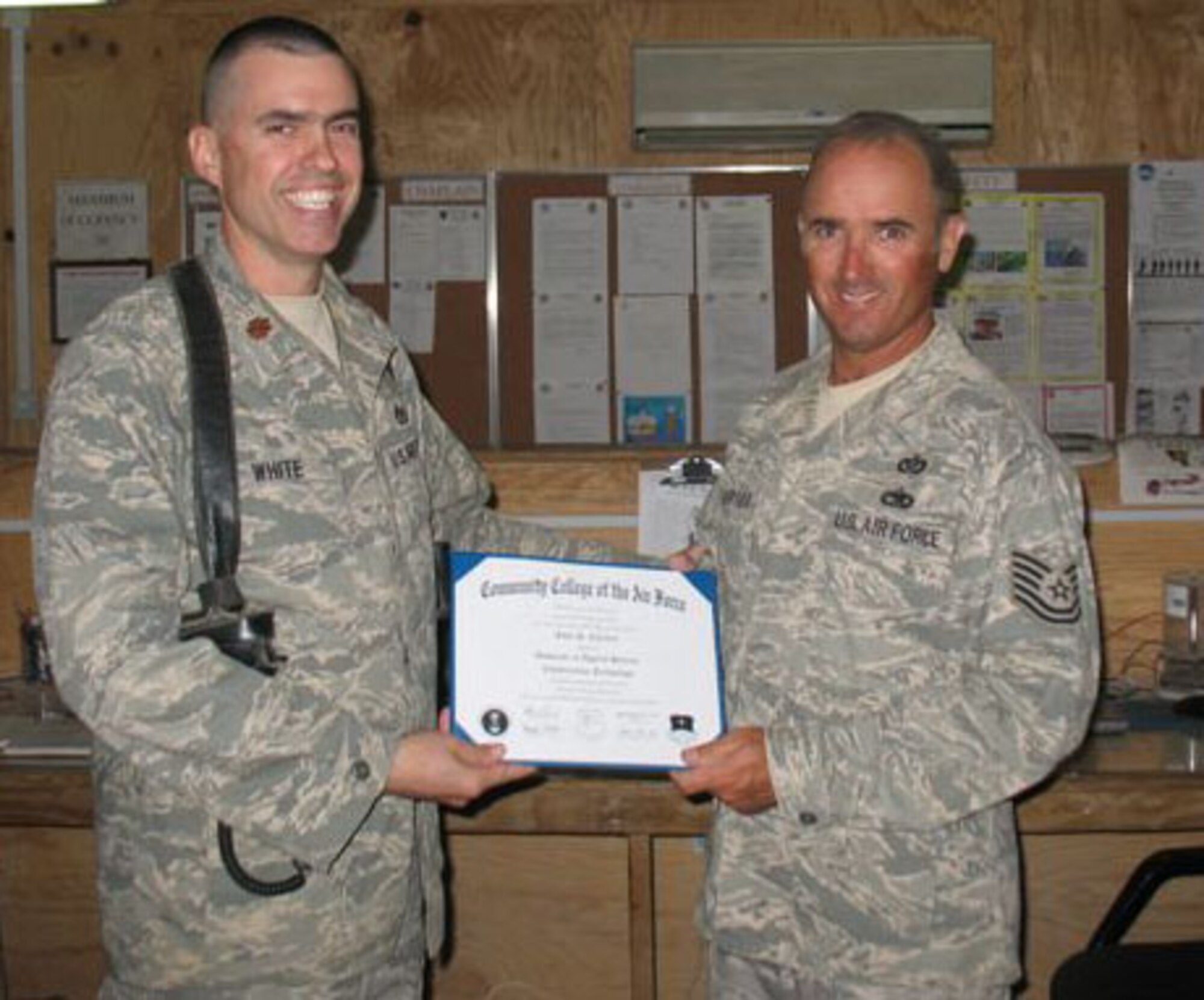 SEYMOUR JOHNSON AIR FORCE BASE, N.C. -- Tech. Sgt. John Chartier (right) receives is Community College of the Air Force degree while stationed at Camp Speicher, Iraq. Sergeant Chartier is a Reservist with the 916th Civil Engineer Squadron and works as a pavement and heavy equipment apprentice.