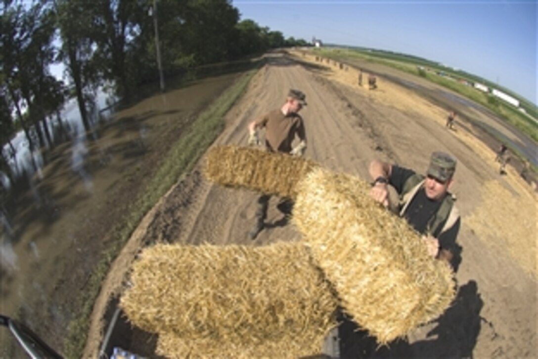 U.S. Air Force Staff Sgts. Troy Martin, right, and Cody Sorenson unload bails of hay to control erosion on about 14,000 acres of farmland near the Mississippi River in Burlington, Iowa, June 18, 2008. Martin and Sorenson are assigned to the Iowa Air National Guard's 185th Services Squadron in Sioux City, Iowa. 
