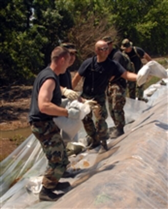U.S. Air Force airmen assigned to the 185th Air Refueling Wing, Sioux City, Iowa, add plastic to a levee north of Burlington, Iowa, as floodwaters continue to rise in the area on June 17, 2008.  Service members have helped raise and reinforce the levee in response to record flood levels effecting eastern Iowa.  The plastic sheeting and sandbags help decrease erosion and hold back the rising floodwaters. The levee is protecting over 100 homes and 50,000 acres of crops from the Mississippi River floodwaters.  Iowa National Guard airmen and soldiers have been activated to work with state and local agencies to provide security and help recover areas damaged by widespread flooding.  