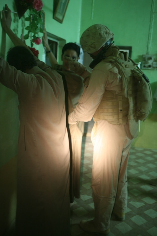 Telling a suspected insurgent to face towards the wall, Gunnery Sgt. Daniel T. Jones, a platoon sergeant with Mike Battery, 3rd Battalion, 14th Marine Regiment, 2nd Light Armored Reconnaissance Battalion, Regimental Combat Team 5, searches for any concealed weapons during a cache search in the city of Rutbah, Iraq, June 20. The battery, known as 'Excalibur,' searched a suspect's house in Rutbah to ensure the safety of the people and to defeat the insurgency.