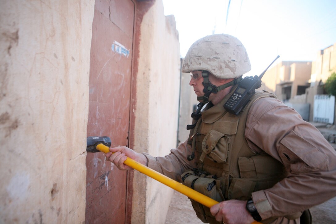 Gunnery Sgt. Daniel T. Jones, a platoon sergeant with Mike Battery, 14th Marine Regiment, 2nd Light Armored Reconnaissance Battalion, Regimental Combat Team 5, hammers a door to a storage space during a cache search in Rutbah, Iraq, June 20. Although the city of Rutbah has become safer, the insurgency is still out there and the Marines with the Chattanooga, Tenn., based unit will be there to there to find them.::r::::n::