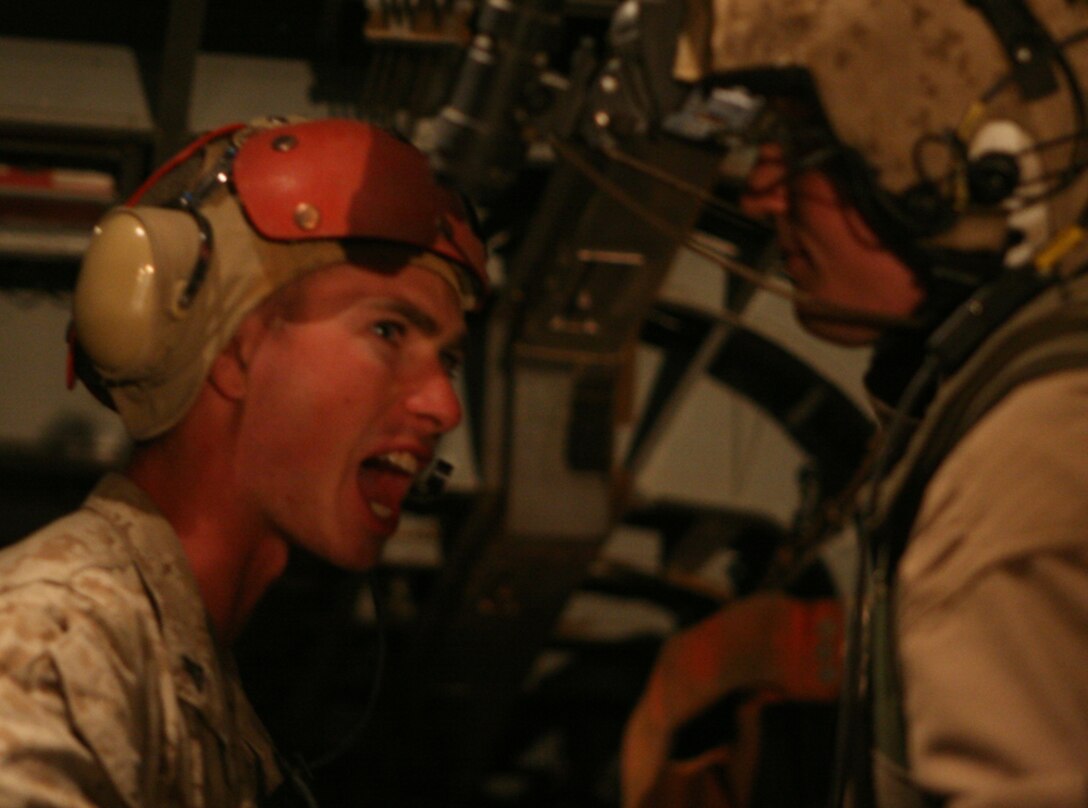 Lance Cpl. Will Cumming, a machine gunner with Headquarters and Service Company, Task Force 2nd Battalion, 2nd Marine Regiment, Regimental Combat Team 5, yells over the roar of a CH-53E Super Stallion Helicopter to one of its crewmembers at Combat Outpost Rawah, Iraq, June 20. Upon arrival at COP Rawah, Cumming took over the task of tracking personnel and cargo coming and going by helicopter.  "He's been doing very well, and he's a very smart kid," said Capt. Travis Unser, a forward air controller with the battalion and Cumming's supervisor on the flight line. "We have received compliments from pilots on how smooth things run here."