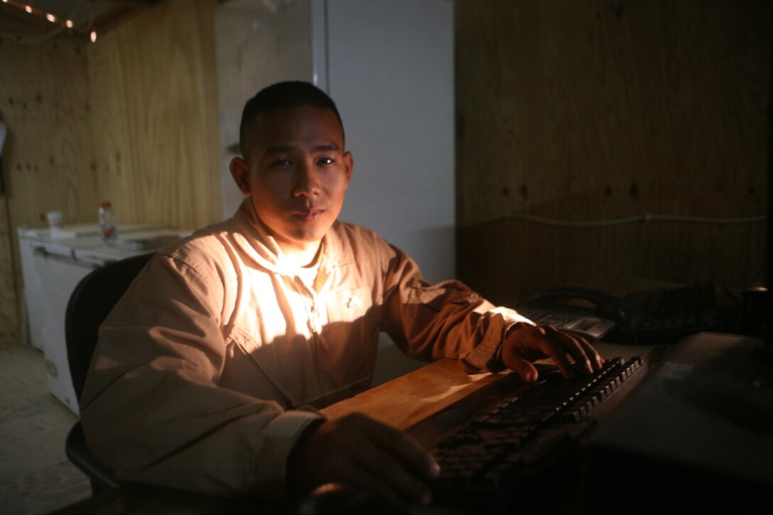 Cpl. Seth Chimm, Biometrics Automated Toolset supervisor of Mike Battery, 3rd Battalion, 14th Marine Regiment, Regimental Combat Team 5, stands in his computer lab, his favorite place to relax in Rutbah, Iraq, June 23. The 24 year old from Chattanooga, Tenn., was born in a Philippine refugee camp after his parents fled Cambodia. Chimm joined the Marine Corps because he feels he owes the United States for giving his family a home.::r::::n::