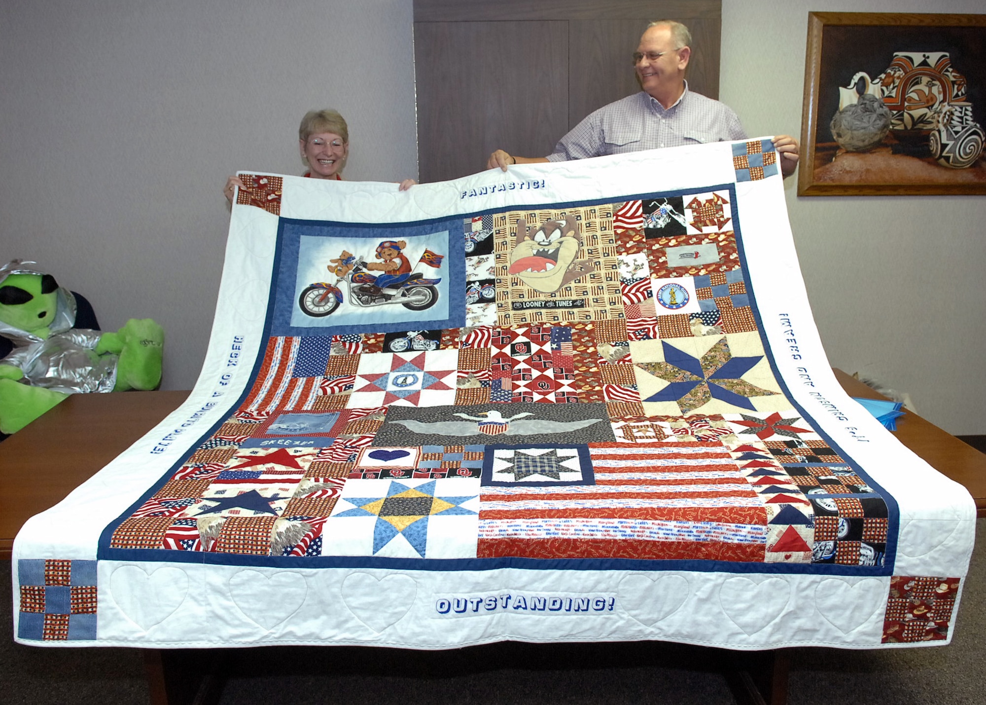 CANNON AIR FORCE BASE, N.M. -- Connie and Rodney Bachman from Garden City Kan., hold up one of the quilts made in their son's memory by the Caprock Quilters during a presentation June 20. Sgt. 1st Class Sergeant First Class Travis was killed by an improvised explosive device on Aug. 1, 2007. (Air Force photo by Airman 1st Class Danielle Martin)