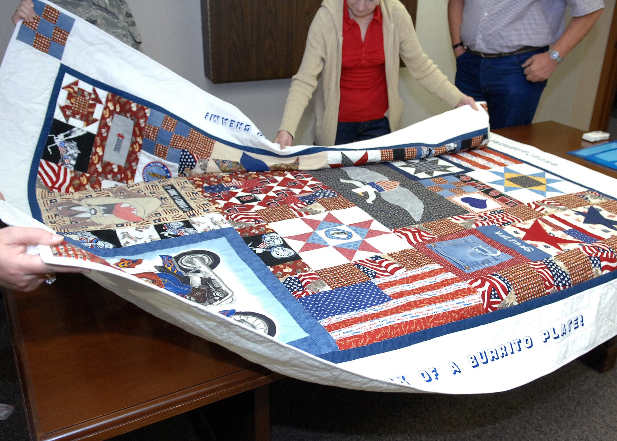 CANNON AIR FORCE BASE, N.M. -- Family and friends of Sgt. 1st Class Travis Bachman,open one of the three quilts presented to them June 20. The Caprock Quilters made six quilts for Sgt. 1st Class Bachman's family, whose parents came to Clovis, N.M. for the presentation. Sgt.1st Class Bachman was killed by an improvised explosive device on Aug.1, 2007. (Air Force photo by Airman 1st Class Danielle Martin)