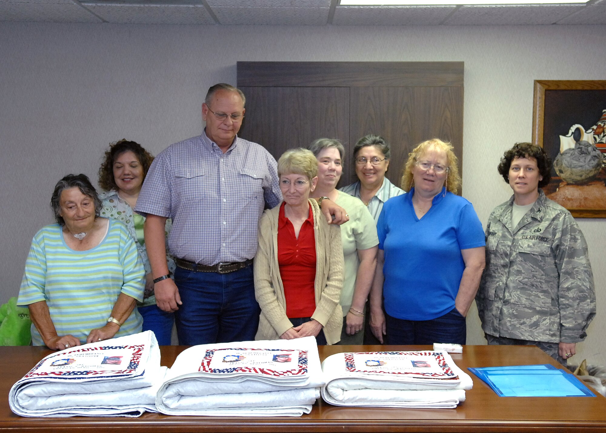 CANNON AIR FORCE BASE, N.M. -- Rodney and Connie Bachman, center, stand over three memorial quilts made in honor of their son. Sgt. 1st Class Travis Bachman killed in Iraq in August 2007. They are flanked by Airmen and Family Readiness Center volunteers and workers and Col. Babette Lenfant, 27th Special Operations Mission Support Squadron commander, The Caprock Quilters presented six quilts to the family. (Air Force photo by Airman 1st Class Danielle Martin)