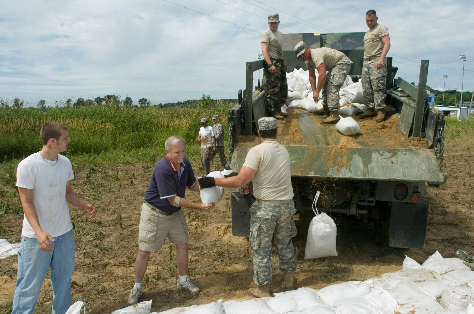 Missouri Army National Guard members and local civilians unload a truck full of sandbags June 20 used to prevent erosion of a levee near Winfield, Mo.. The Soldiers are assigned to 1140th Engineering Battalion out of Cape Girardeau, Mo. (U.S. Air Force photo/Staff Sgt. Desiree Palacios)