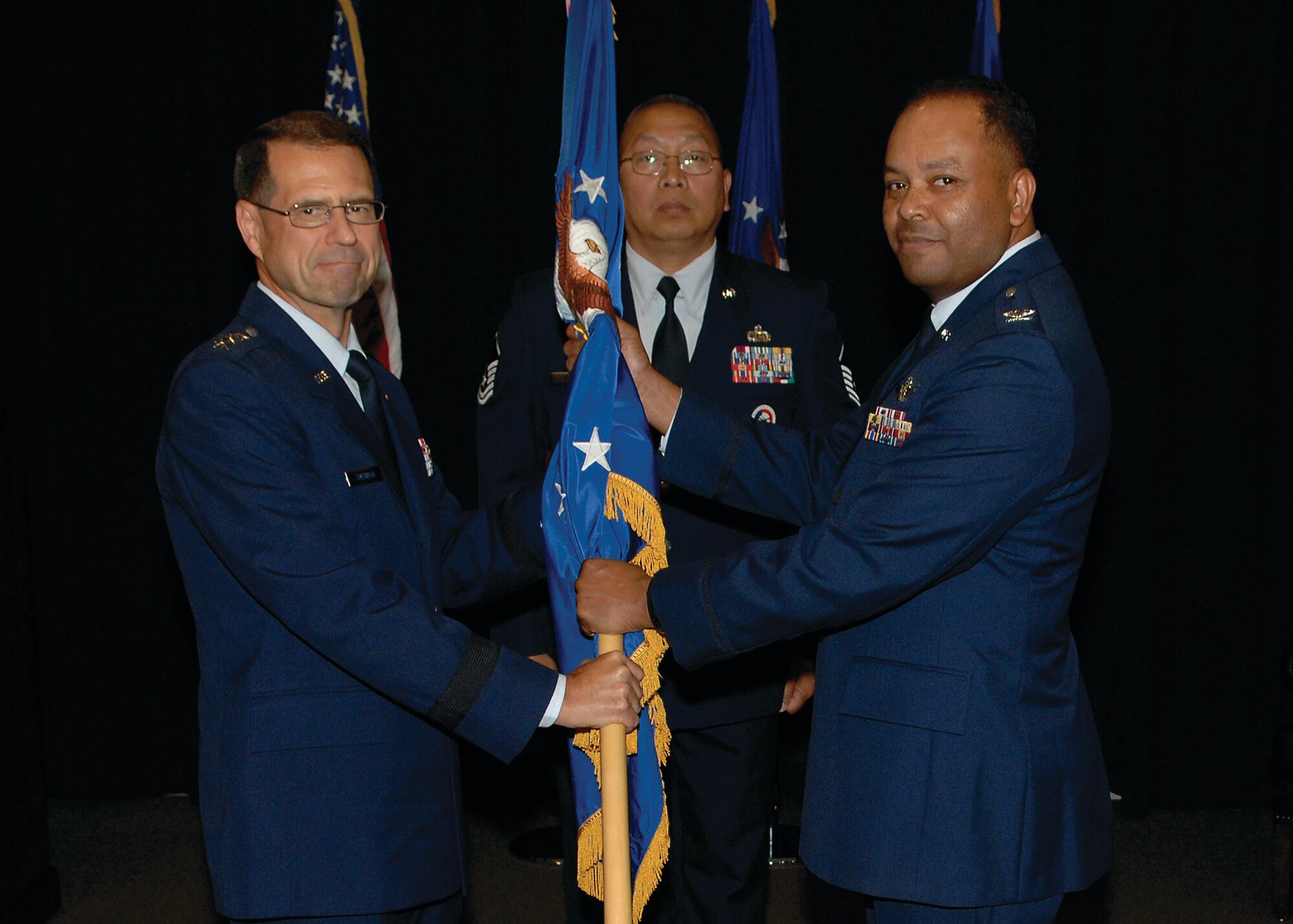 Col. Samuel Greaves accepts the SMC/Military Satellite Communications Wing guidon from AFSPC/SMC Commander, Lt. Gen. John T. 'Tom' Sheridan signifying his acceptance of command as the new commander of Space and Missile Systems Center Military Satellite Communications Wing. Colonel Greaves  was formerly commander of the SMC Launch and Range Systems Wing. (photo by Stephen Schester)