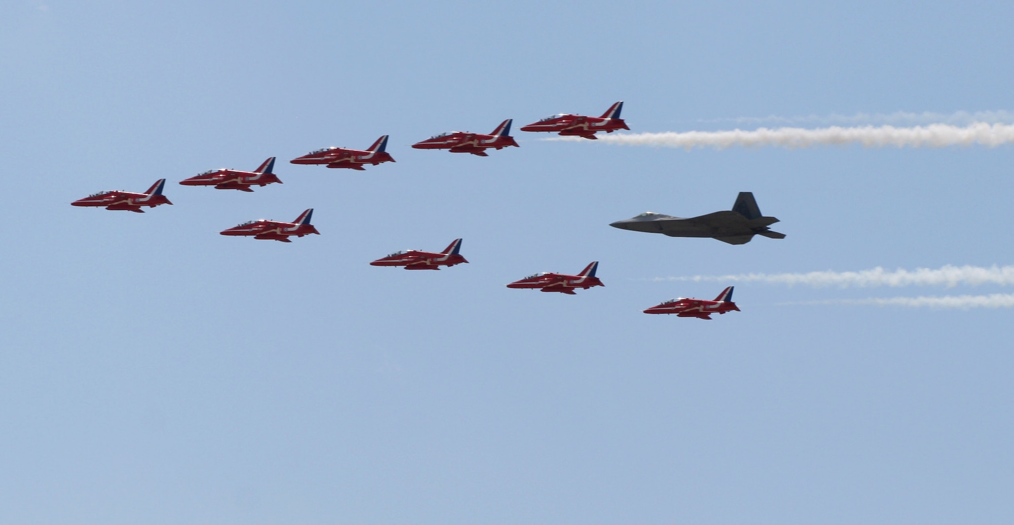 Maj. Paul Moga in an F-22 Raptor flies in formation with the Royal Air Force Aerobatic Team, The Red Arrows, during an afternoon practice flight June 18 at Langley Air Force Base, Va. The aircraft will perform at AirPower over Hampton Roads, the Langley AFB airshow, which is scheduled for June 20 to 22. Major Moga is an F-22 Demonstration Team pilot. (U.S. Air Force photo)

