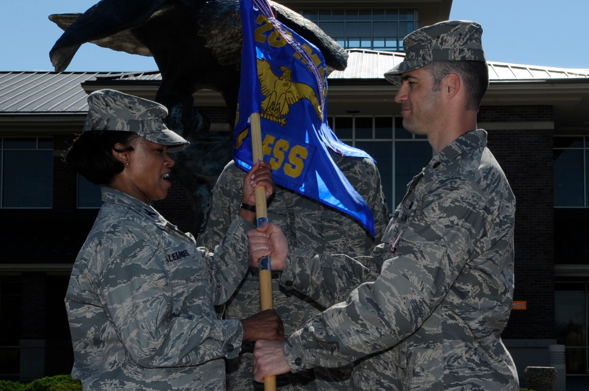 Maj. Patrick Whelan (right), 28th Force Support Squadron commander, relinquishes his command by passing the guidon to Col. Renita Alexander (left), 28th Mission Support Group commander, during a change of command ceremony here, June 19. Major Whelan took command of the 28 FSS April 11 as part of the merger between the 28th Services Squadron and 28th Mission Support Squadron. (U.S. Air Force photo/Airman 1st Class Kasey Zickmund)