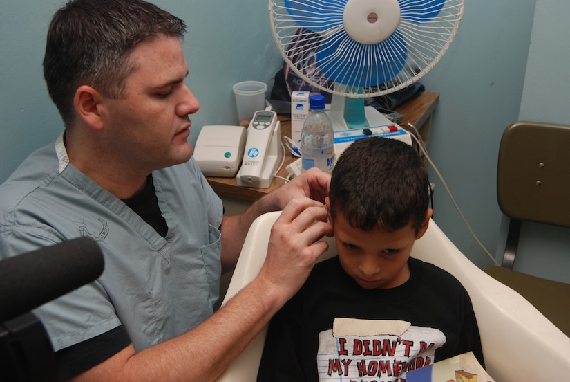 Air Force Capt. Matt Williams, an audiologist from Wilford Hall Medical Center in San Antonio, Texas, treats a young patient at Hospital Escuela in Tegucigalpa, Honduras, June 17. The audiology team performed more than 160 hearing tests and fitted more than 50 hearing aids during their two-week visit to the hospital. (U.S. Air Force photo by Tech. Sgt. John Asselin) 