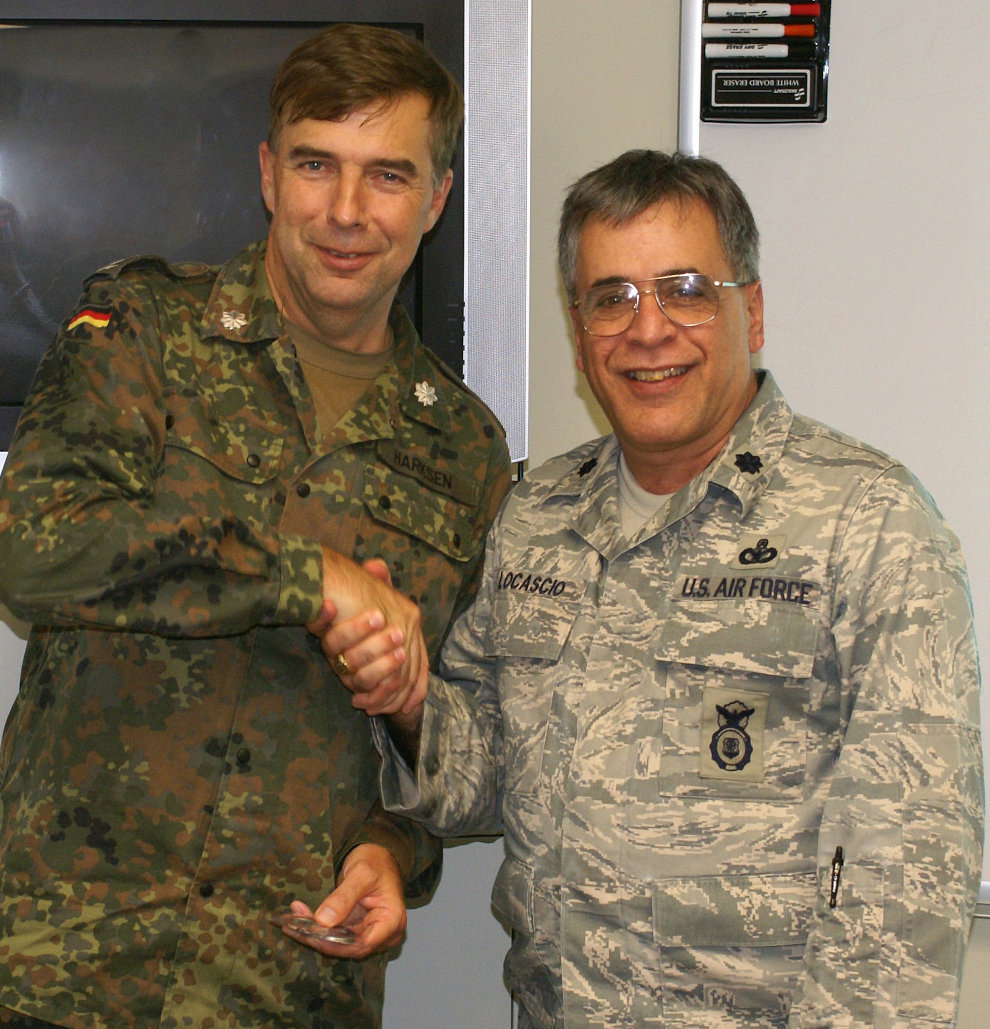 HOMESTEAD AIR RESERVE BASE, Fla. - Lt. Col.  Frank Locascio, 482nd Security Forces Squadron commander, presents a coin to Lt. Col. Christoph Harksen (left), German Air Force Reserve security forces officer, after Colonel Harksen briefed 482nd SFS members about German reserve military forces. Colonel Harksen arrived at Homestead Air Reserve Base on June 14 and will depart on June 21 for a second week at Dobbins Air Force Base, Ga. The visit was through the United States/Germany Reserve Officer Exchange Program. (U.S. Air Force photo/Staff Sgt. Erik Hofmeyer)