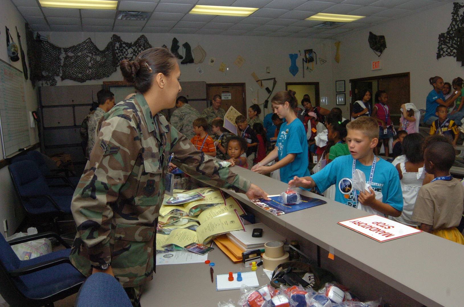 Airman 1st Class Antonieta Jara, 12th Aeromedical-Dental Squadron public health journeyman and Operation FLAGS volunteer, checks 8-year-old Zach Chesley?s mock medical mobility folder as he processed through the mock pre-deployment medical screening at the Public Health and Immunization building. (U.S. Air Force photo by David Terry)