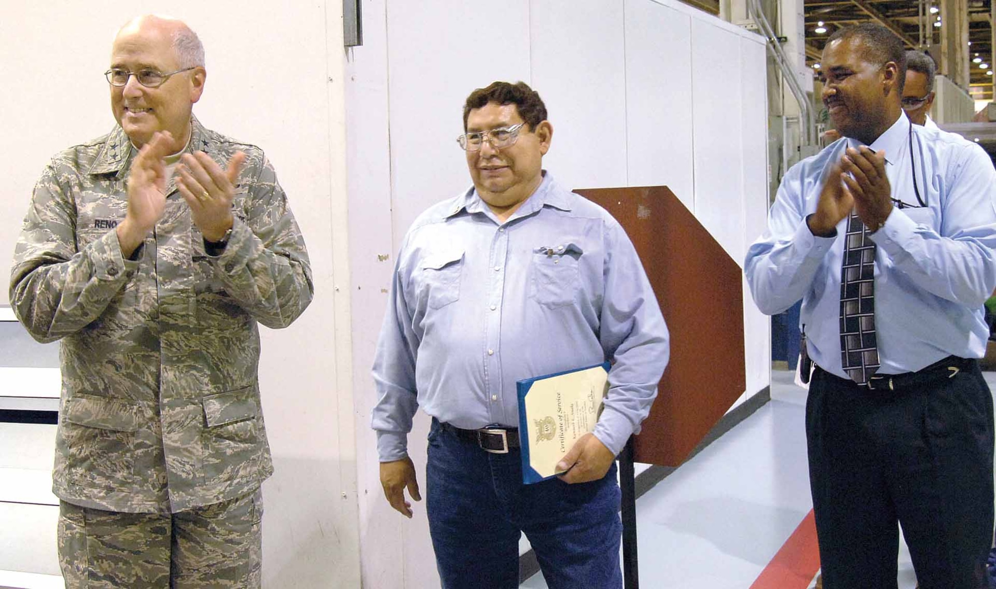 Kenneth Snake, center, celebrates  40 years of service with help from Maj. Gen. Loren Reno, Oklahoma City Air Logistics Center commander, and Stanley McKinney, 544th Production Maintenance flight chief who lead friends and coworkers in applause June 13 near Hollywood and Vine in Bldg. 3001. General Reno thanked the machinist for his dedication before awarding him a 40-year pin and a certificate of service. (Air Force photo by Margo Wright) 
