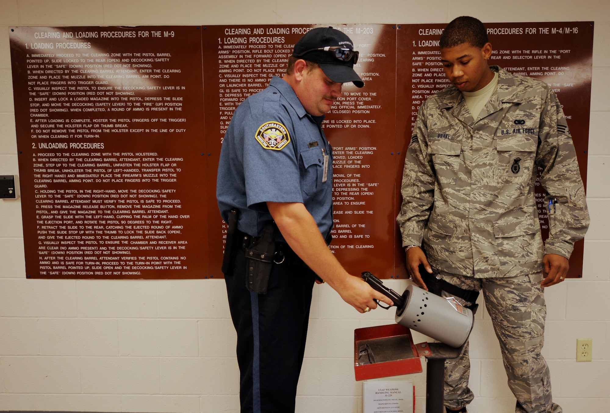 MOODY AIR FORCE BASE, Ga. -- LeRoy Kent, contract gate guard weekend midshift supervisor, clears his weapon while Senior Airman Xavier Drake, 23rd Security Forces armory supervisor, looks on at the armory here June 11. Weapons are cleared for saftey before they are issued and before they are returned to the armory. (U.S. Air Force photo by Senior Airman Gina Chiaverotti)