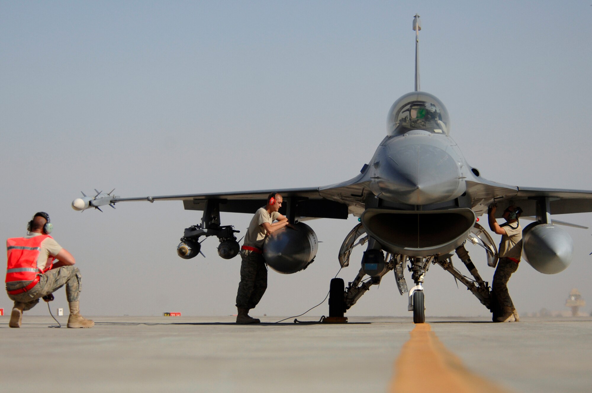 JOINT BASE BALAD, Iraq -- Airmen assigned to the 332nd Expeditionary Aircraft Maintenance Squadron, arm an F-16 Fighting Falcon by removing the safety pins here, June 18. The F-16 pilots provide overhead air support to ground forces which provides them a safer operating area. (U.S. Air Force photo/ Senior Airman Julianne Showalter)