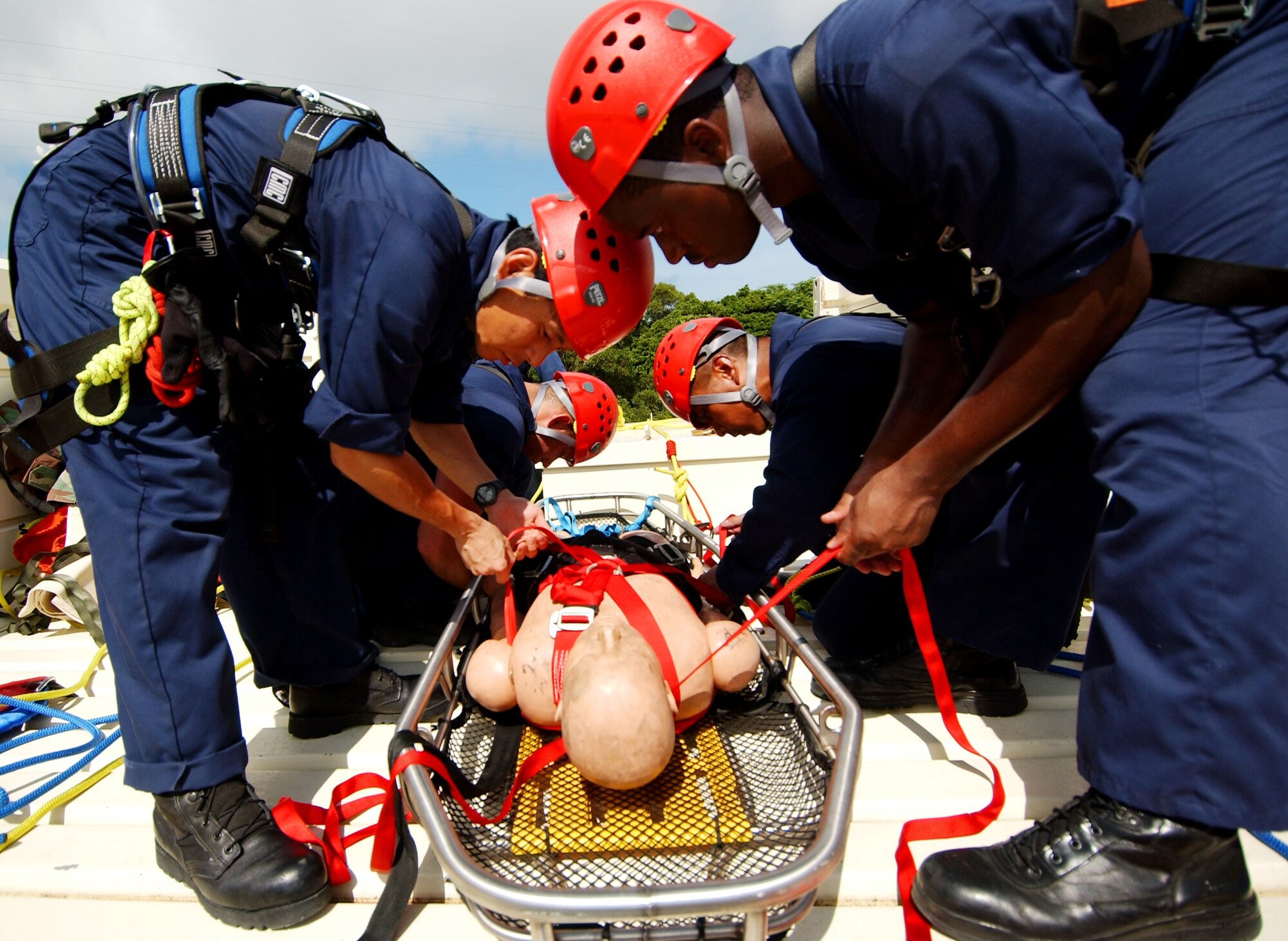 Staff Sgt. Roderick Marquez, 36th Civil Engineer Squadron, Andersen Air Force Base, Guam, and Senior Airman Derek White, 18th Civil Engineer Squadron, Kadena Air Base, Japan, along with other team members secure an unconscious victim on a stokes basket with webbing straps before lowering off the tower, June 17.  (U.S. Air Force/Tech. Sgt. Rey Ramon)