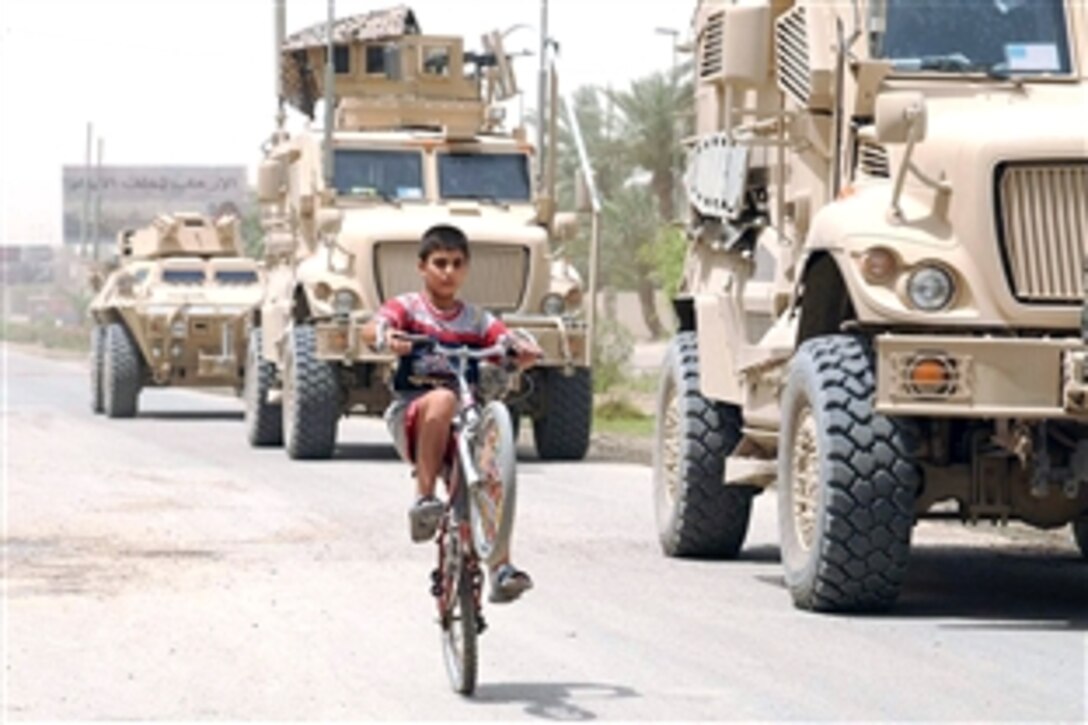 An Iraqi boy pops a "wheelie" along Route Texas while riding past a U.S. Army vehicle patrol of military policemen assigned to the4th Infantry Division's 3rd Battalion Combat Team, June 17, 2008. 