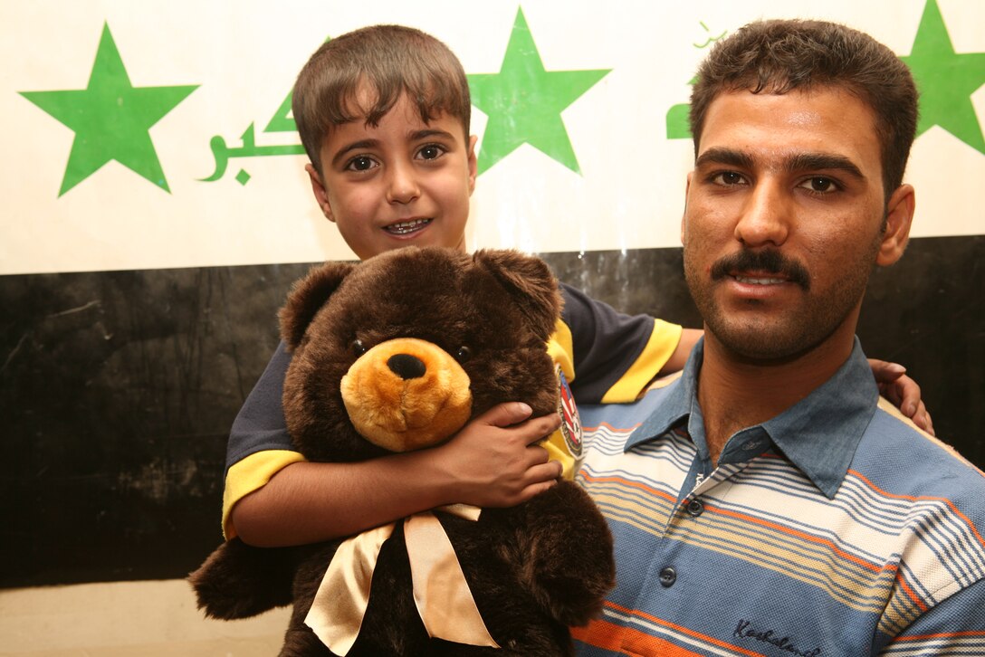 Five-year-old Ahmed and his father, Warrant Officer Othman Mallouki, an Iraqi policeman with Fallujah Headquarters District, enjoy time spent together during an afternoon with Marines from Company B, Police Transition Team 8, Regimental Combat Team 1, at the Joint Command Center June 21. (Official Marine Corps photo by Cpl. Chris T. Mann)