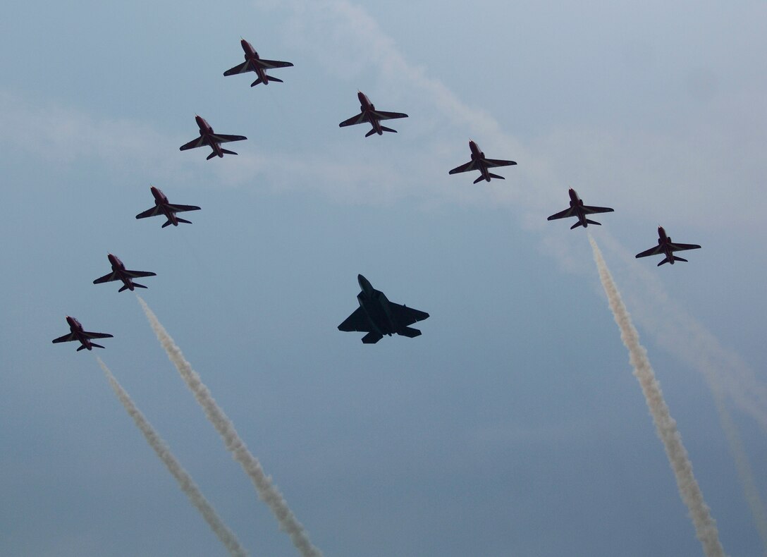 LANGLEY AIR FORCE BASE, Va. -- An F-22 Raptor flies in formation with the Royal Air Force Red Arrows during AirPower over Hampton Roads here June 21. Langley’s open house is an annual event that helps educate the public, increase recruiting and show appreciation to the local community.  “It's a chance to get people informed, involved and excited,” said Lt. Col. Brady Merrill, director of AirPower over Hampton Roads and chief of 1st Fighter Wing Plans, Programs and Evaluations. (U.S. Air Force photo/Tech. Sgt. Levi Collins)