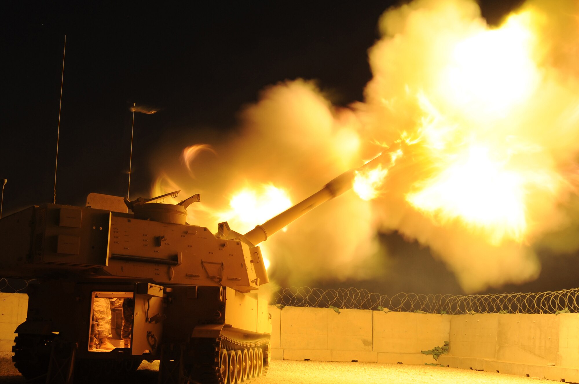 ALI BASE, Iraq - Col. David Mansfield, 407th Air Expeditionary Group commander fires an illumination round from a M-109A6 Paladin Self Propelled Howitzer here June 20 in support of Iraqi Police patrolling Nasiriyah, Iraq. The Soldiers of the 3-319th Airborne Field Artillery Regiment, 1st Brigade Combat Team, 82nd Airborne Division, regularly support Iraqi Police with illumination to help them secure the city. Col. Mansfield was given a tour, a system capability brief and the opportunity to fire, under close Soldier supervision, so that he can better inform Airmen about the "outgoing fire" missions and thunderous explosions heard almost nightly here. (U.S. Air Force photo by Staff Sgt. Nathan Gallahan)